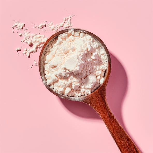 A close up of a scoop of protein powder against a pink background