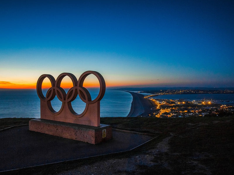 The Olympic rings set against a coastal backdrop